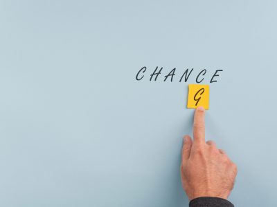 Male hand changing the word Change into Chance. Over blue background with plenty of copy space.